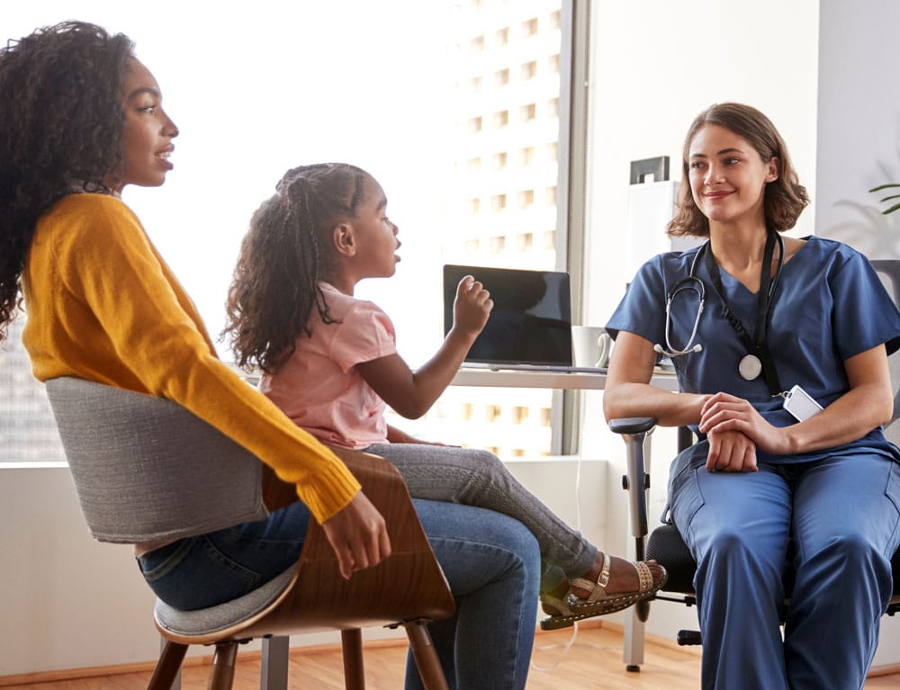 Nurse Practitioner listening to child and mother in office