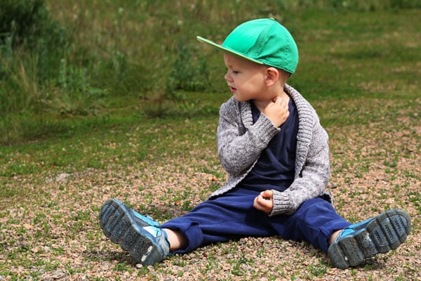 Child sitting on the ground scratching mosquito bites.