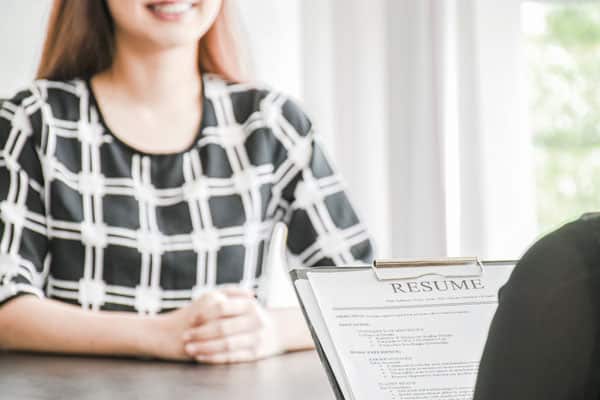 Employer or boss is interviewing for jobs and positions. Woman sitting smiling while submitting a resume document.