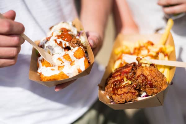 Person holding a tray of Fried chicken and chips in a food festival