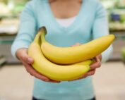Close up of woman's hands holding a bunch of bananas in a grocery store produce section