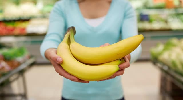 Grocery Store Close up of woman's hands holding a bunch of bananas in a grocery store produce section