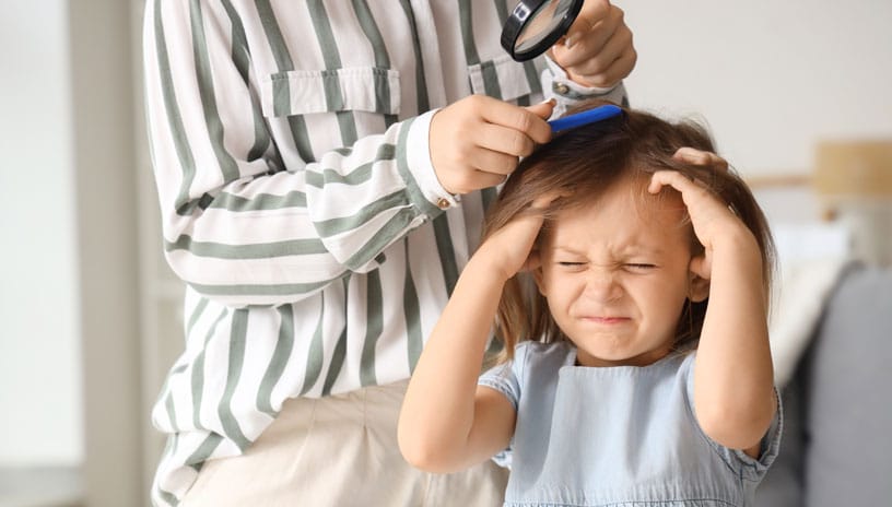 Woman inspects and brushes out lice from young girl with an itchy head.