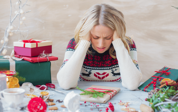Woman stressed over the holidays surrounded by gifts and packages.