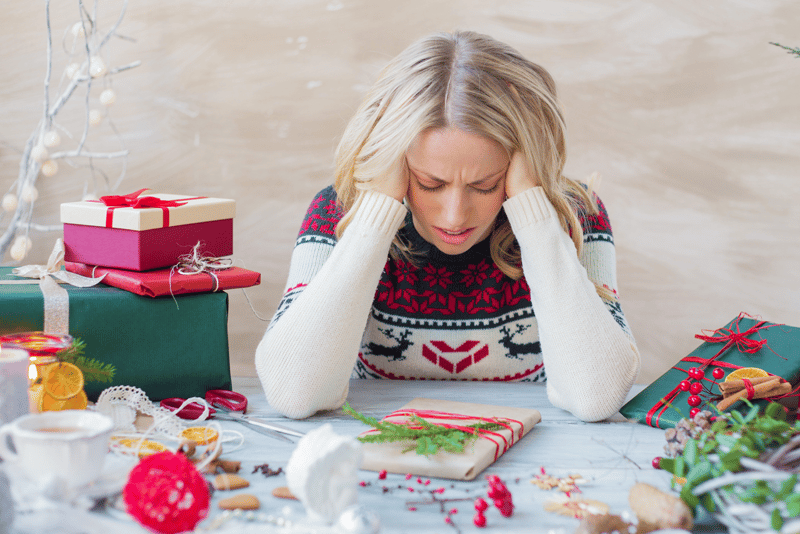 Woman stressed over the holidays surrounded by gifts and packages.