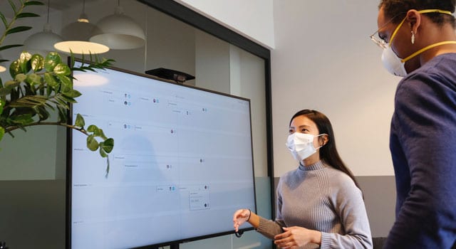 business guidance phase 4 masked woman standing in front of a large white board in an office setting
