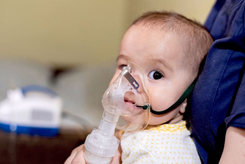 closeup of baby inhaling fumes spray of the medication