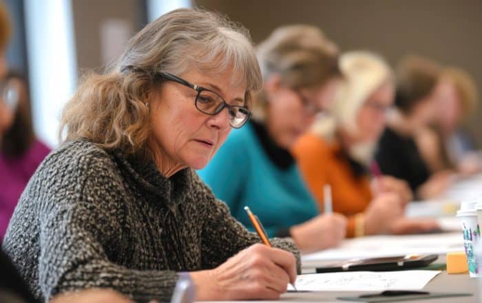 Older woman sitting at desk writing.