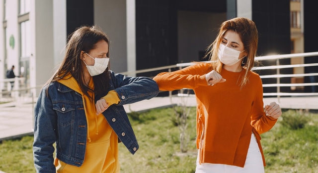 friends elbow bump while wearing face masks friends elbow bump while wearing face masks