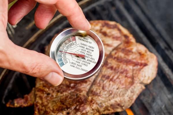 grilled meat on bbq with hand holding meat cooking