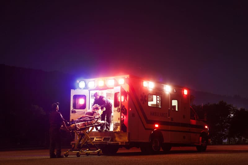 paramedics carrying patient in ambulance at night