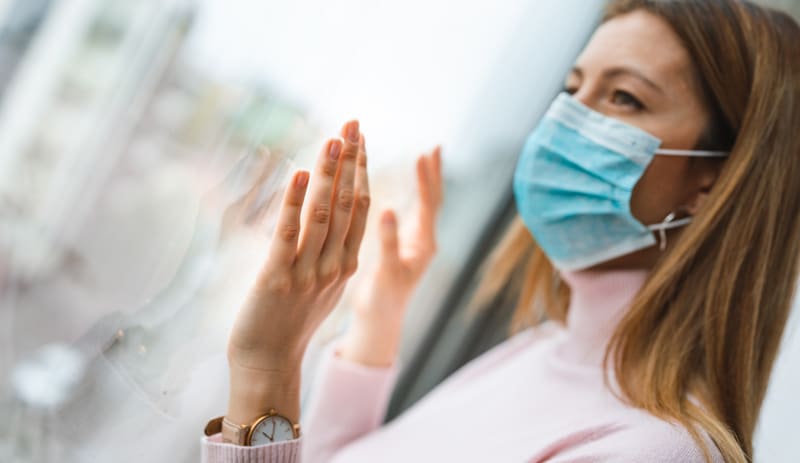 woman wearing mask looking out a window woman wearing mask looking out a window