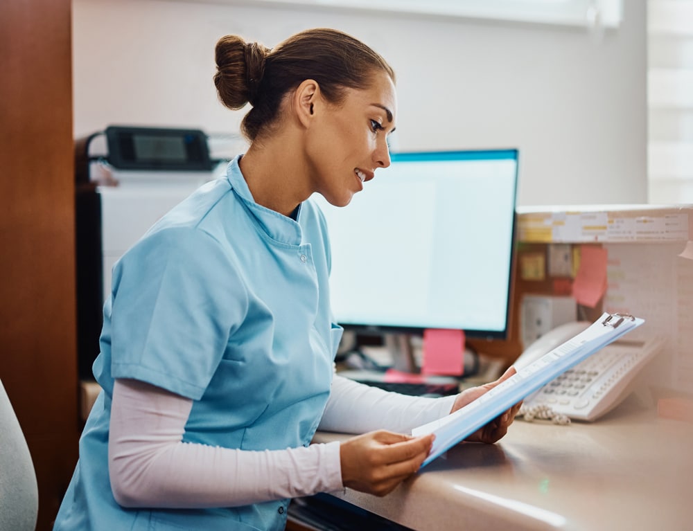 young-nurse-going-through-medical-records-at-recep_web